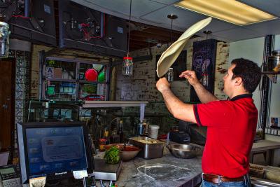 Pizzaiolo tossing fresh pizza doough